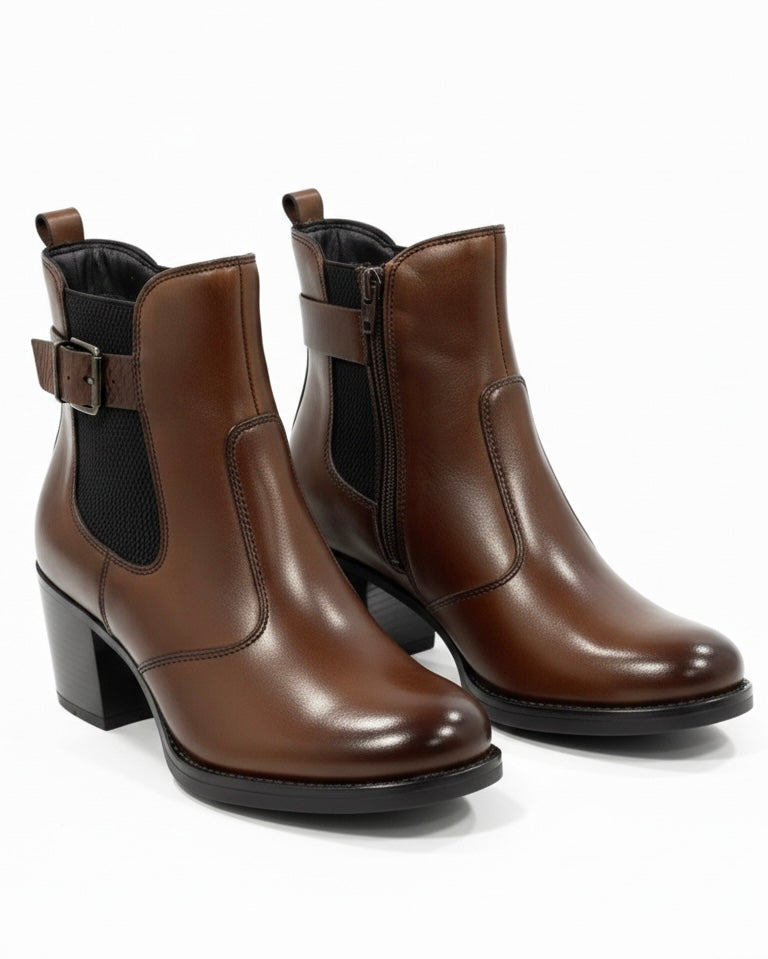 Stivaletti chelsea da donna in pelle marrone scuro con tacco largo e fibbia laterale decorativa.