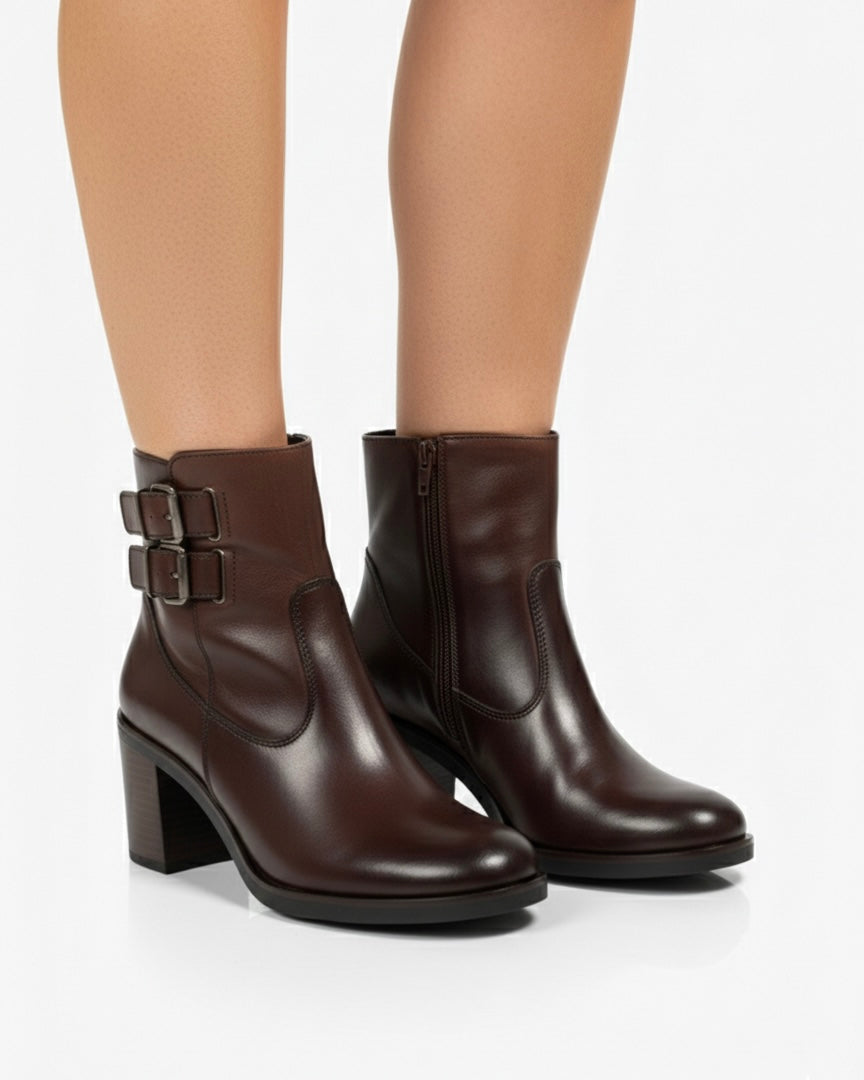 Stivaletti marrone scuro in pelle liscia con doppio cinturino laterale, fibbie metalliche brunite e tacco largo effetto legno - indossate.